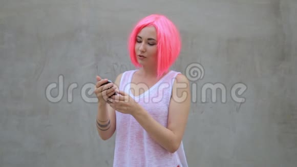美丽的混血女人戴着粉色假发发短信用电话微笑旋转享受生活视频的预览图