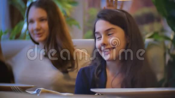 在咖啡馆里交流的女孩是朋友孩子们坐在咖啡馆里快餐慢动作视频在室内视频的预览图
