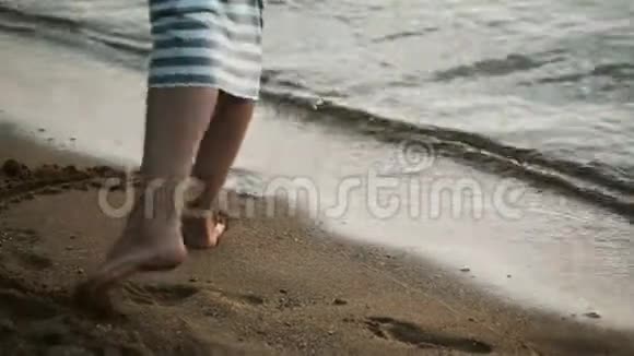近景男女双脚站在海边年轻夫妇在海滩上的沙滩上画画视频的预览图