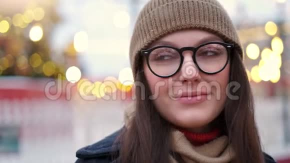 美丽的女人站在城市广场的圣诞装饰和直视镜头视频的预览图