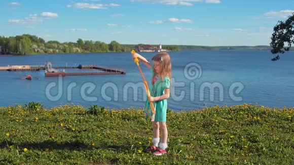 在海岸的背景下金发小女孩膨胀了巨大的肥皂泡视频的预览图
