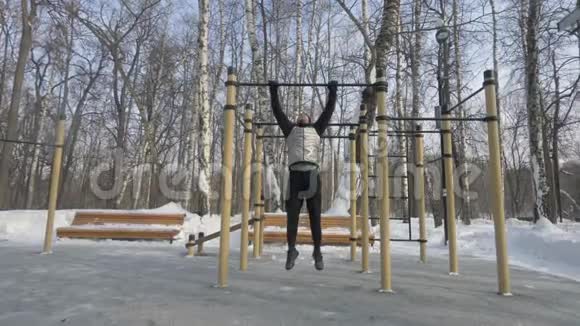 冬季体育锻炼期间年轻人在横杠上做拉力锻炼视频的预览图