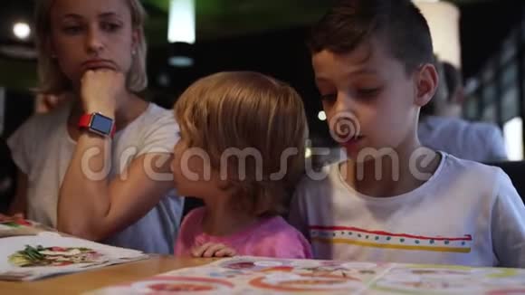 带着孩子的妈妈在咖啡馆里挑选比萨饼玩得开心视频的预览图