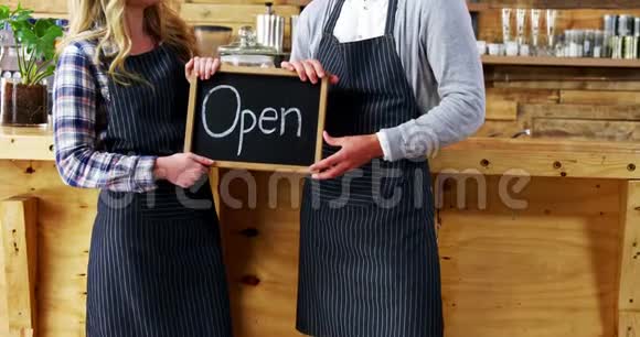 微笑的侍者和服务员拿着开放的招牌视频的预览图
