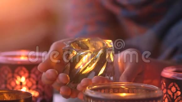 女性双手握着透明玻璃中的蜡烛在黑暗中闪耀作为庆祝冥想的象征视频的预览图