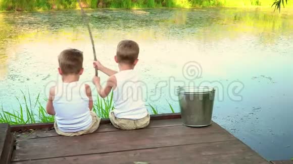 两兄弟在露天捕鱼男孩子们穿着白色的裙子钓鱼视频的预览图