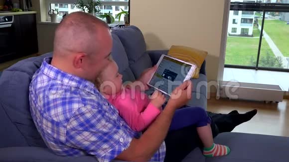 快乐爸爸和宝贝女儿在平板电脑上听音乐视频的预览图