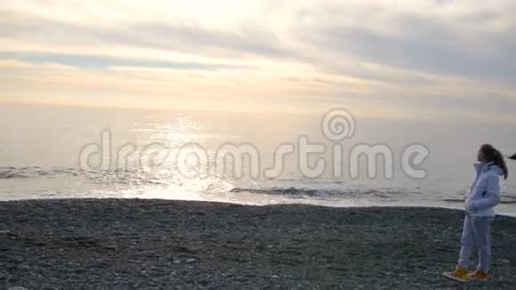 金发碧眼的女人穿着白色夹克在海边散步视频的预览图
