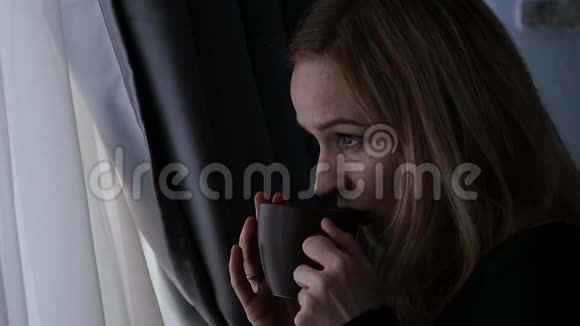 漂亮的女人喝咖啡或茶看着窗外慢动作视频的预览图