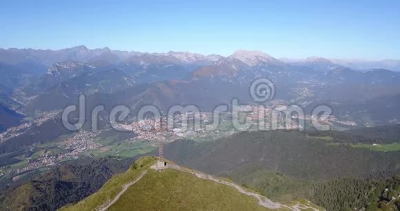在一个晴朗而蓝色的日子里可以看到塞里亚纳山谷和奥罗比阿尔卑斯山的无人机空中景色山顶的十字架视频的预览图