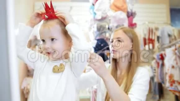 孩子们的服装店金发小女孩和妈妈一起购物买红帽子视频的预览图