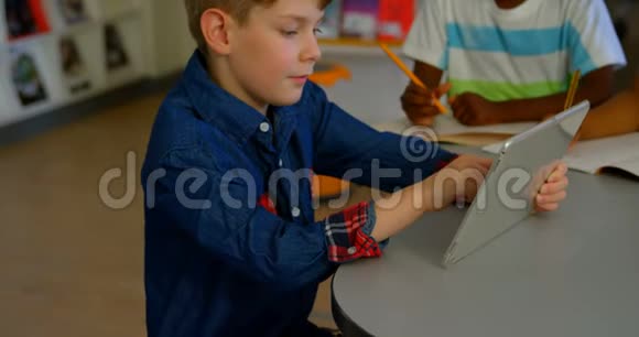白人学童在学校图书馆使用数码平板电脑4k视频的预览图