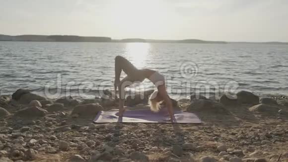 那个美丽的运动女子在海滨做早操海滩和日出的背景视频的预览图