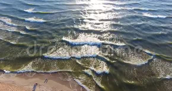 日落时在白沙滩上的鸟瞰海浪拍打陆地与大海交汇视频的预览图