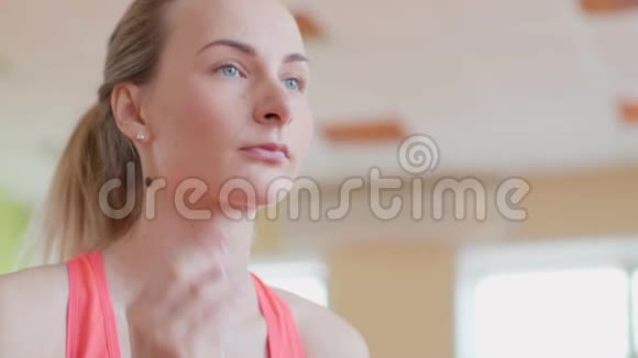 穿着运动服戴着耳机的漂亮女孩在运动后休息时一边听音乐一边喝水视频的预览图