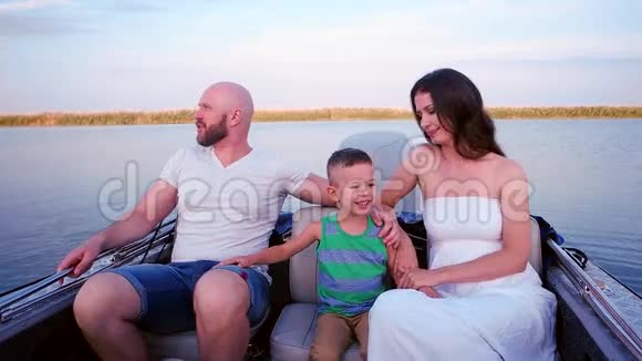 幸福的一家人走在水边父母带着一个孩子在夏天郊游爸爸妈妈是儿子的手视频的预览图