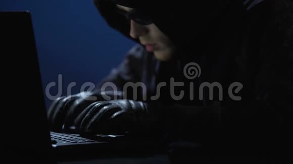 穿着黑色衣服戴着墨镜和手套的奇怪男人从笔记本电脑上偷取数据视频的预览图