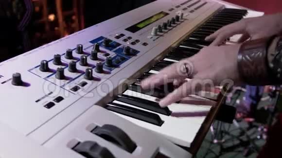 这位音乐家用彩色聚光灯在夜总会里演奏合成器一个男性键盘播放器在聚会上表演视频的预览图