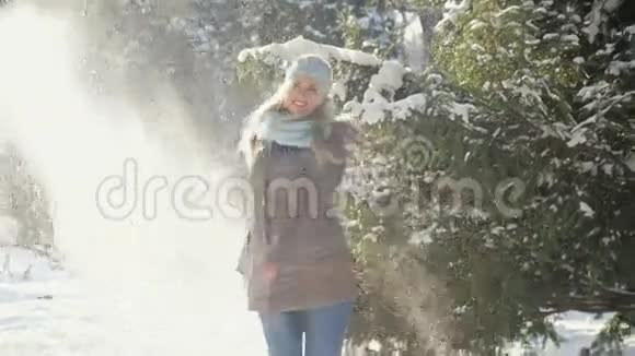 迷人的年轻女子在公园散步享受雪花从树上飘落舒适的寒假概念视频的预览图