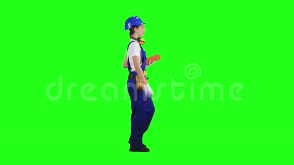 女建筑工人携带一块砖进行施工绿色屏幕侧视图视频的预览图