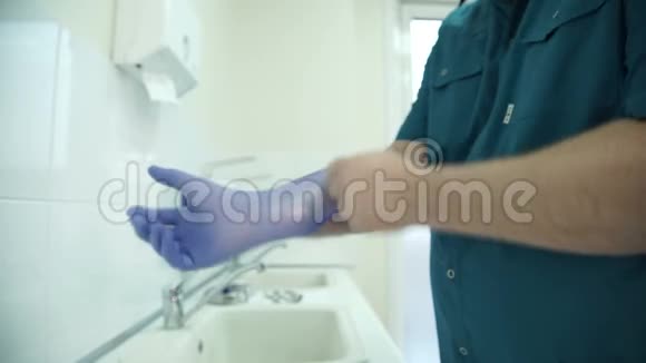医生在洗手池穿衣服并矫正紫色无菌手套视频的预览图