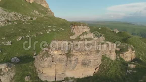 绕着一个巨大的岩层飞行站在岩石高原史诗边缘的脚下俄罗斯北高加索视频的预览图