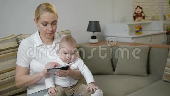 一名妇女带着一个小孩家里有平板电脑和信用卡视频的预览图