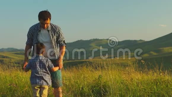 父亲抱着儿子在风景优美的背景下转身视频的预览图
