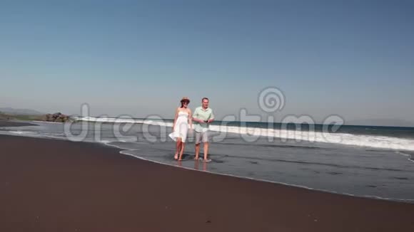 4K航天飞行视频的年轻夫妇在海滩与黑色火山沙在日落时间巴厘岛视频的预览图