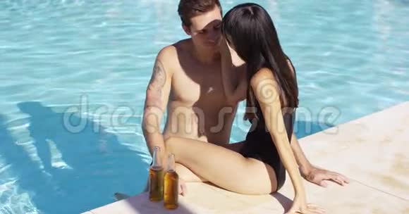 有瓶装饮料的女人坐在泳池边视频的预览图