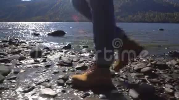 阿尔泰两个视频合一露营妇女坐在山湖畔穿着登山靴的女孩的脚视频的预览图