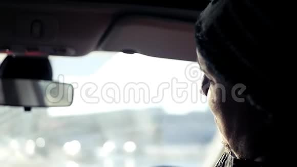 一位驾驶汽车的年轻司机在明亮的阳光下环游城市交谈高清慢动作1920x1080视频的预览图