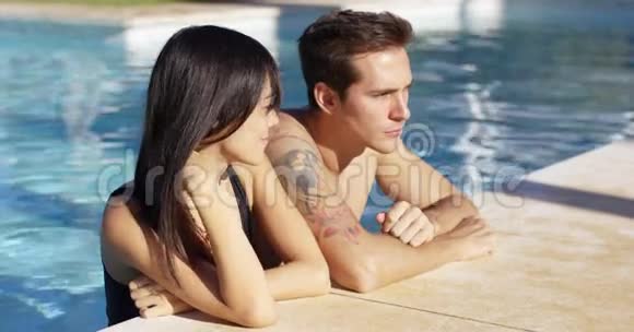 一对长相英俊的情侣站在游泳池里视频的预览图