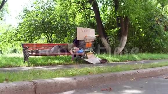 城市公园里睡在长凳上的老乞丐的景色视频的预览图