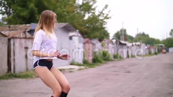 运动的年轻金发女人穿短裤在轮胎的帮助下进行各种力量练习跳跃在夏天视频的预览图