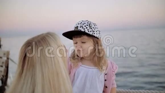 年轻的母亲和她的小女儿在海边码头接吻视频的预览图
