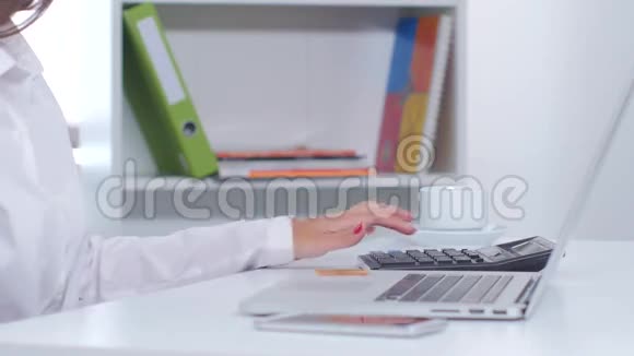 办公室里的女孩用计算器计算网上购物的费用关门视频的预览图