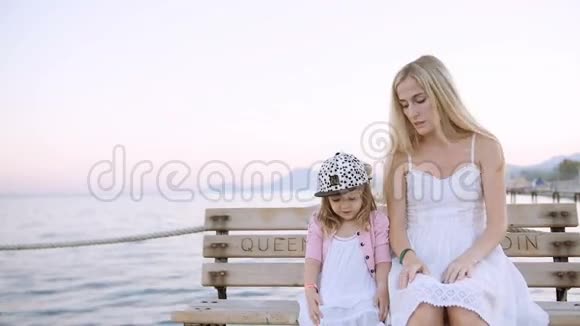 妈妈和女儿坐在码头上的沙滩长椅上视频的预览图