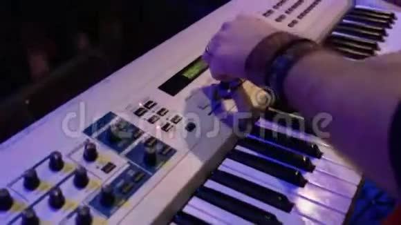 合成器后面的人玩钥匙一个摇滚乐队在夜总会聚会上表演视频的预览图