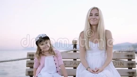 妈妈和女儿坐在码头上的沙滩长椅上视频的预览图