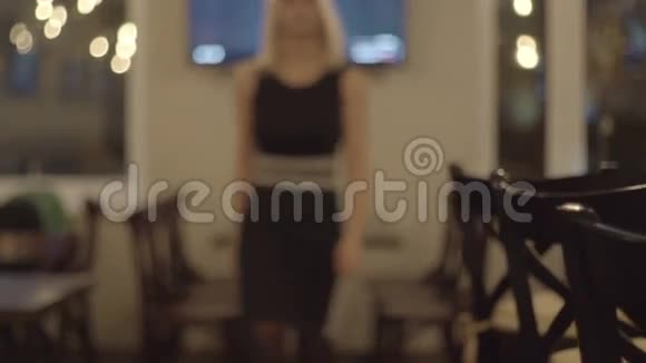 穿着黑色裙子的女孩从酒吧柜台走过坐在椅子上视频的预览图