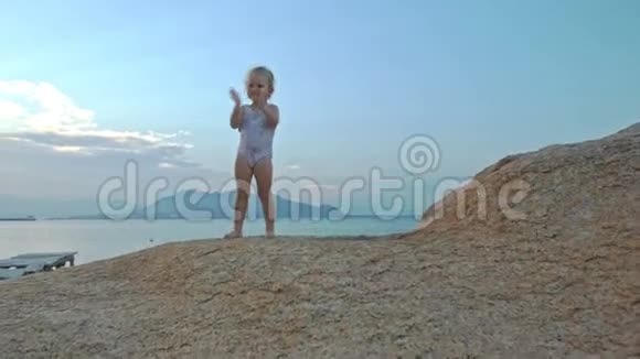 小女孩站在沙滩上的夕阳下的山顶拍手视频的预览图