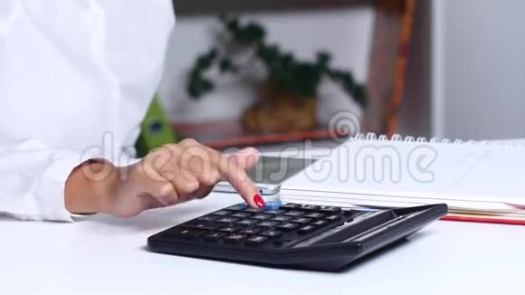 女孩把计算记录在计算器上获得的笔记本上关门视频的预览图
