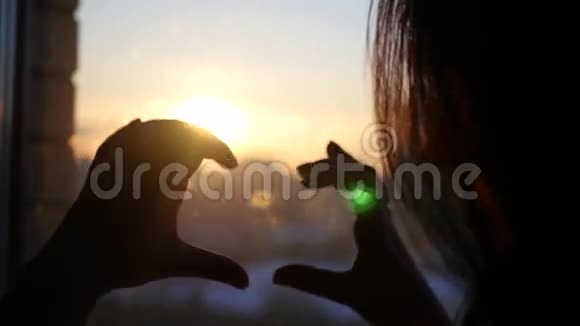 指尖构成浪漫的心在窗外美丽日落的背景下4K视频的预览图