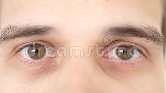 一个惊讶的情感男人的特写棕色的眼睛看着镜头慢动作3840x2160视频的预览图