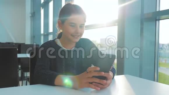 十几岁的女孩正在聊天在一个桌子阳光下的咖啡馆里在智能手机里的信使里交流青少年视频的预览图