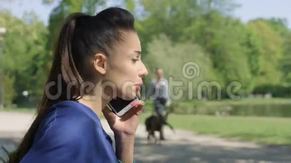 在阳光公园里一幅不开心的心烦意乱的年轻女人在手机上聊天的肖像视频的预览图