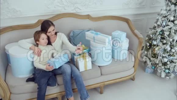 年轻的母亲和快乐的儿子拿着圣诞礼物在电话里自拍视频的预览图