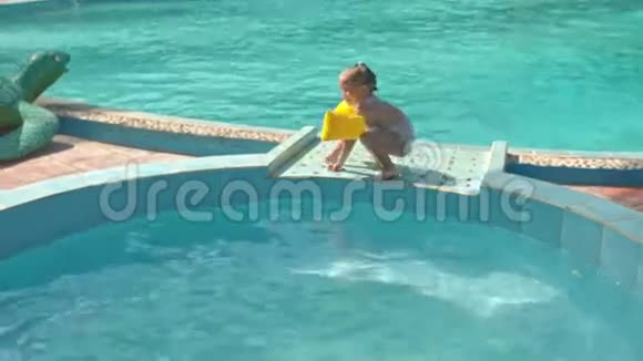 小女孩在玩具海龟的障碍树桩上漫步进入游泳池视频的预览图