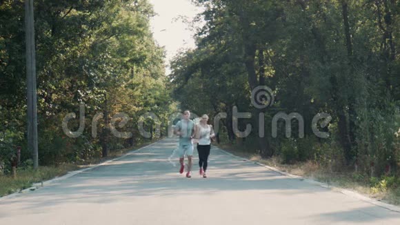 一对夫妇在森林路上奔跑前景视频的预览图